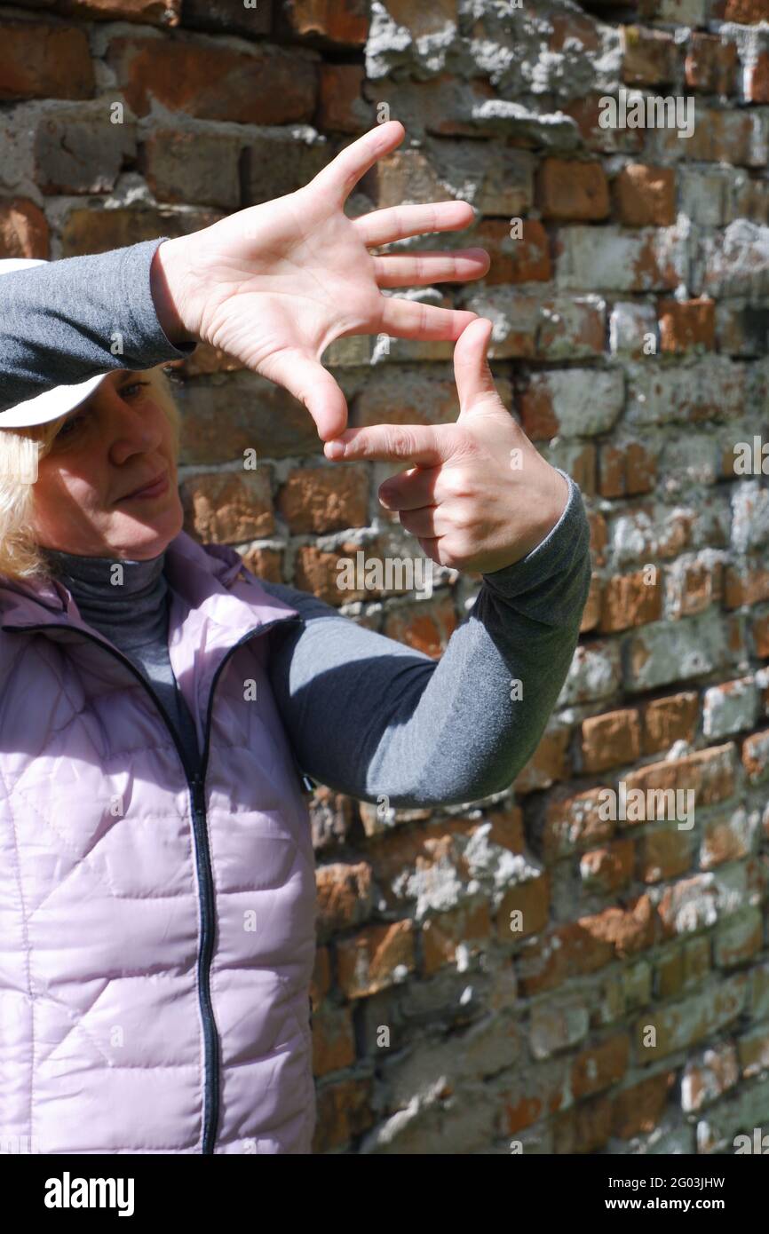 Une fille près d'un mur de briques avec ses mains imagine un appareil photo. Journée des photographes de la Saint-Veronica . Banque D'Images