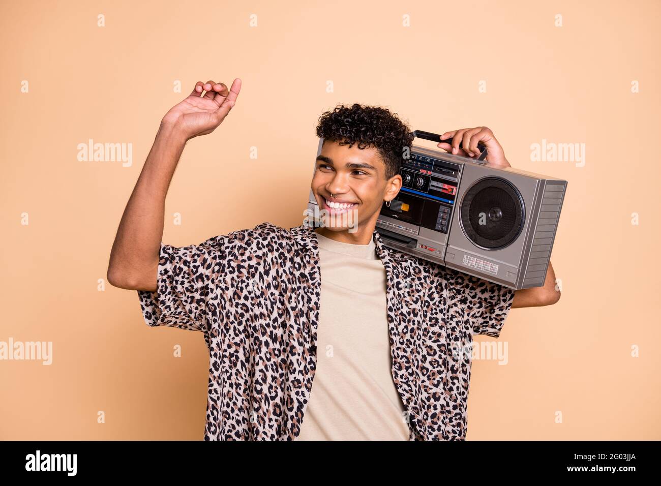 Photo de brunet optimiste gars écouter boîte de perche porter moderne chemise isolée sur fond beige Banque D'Images