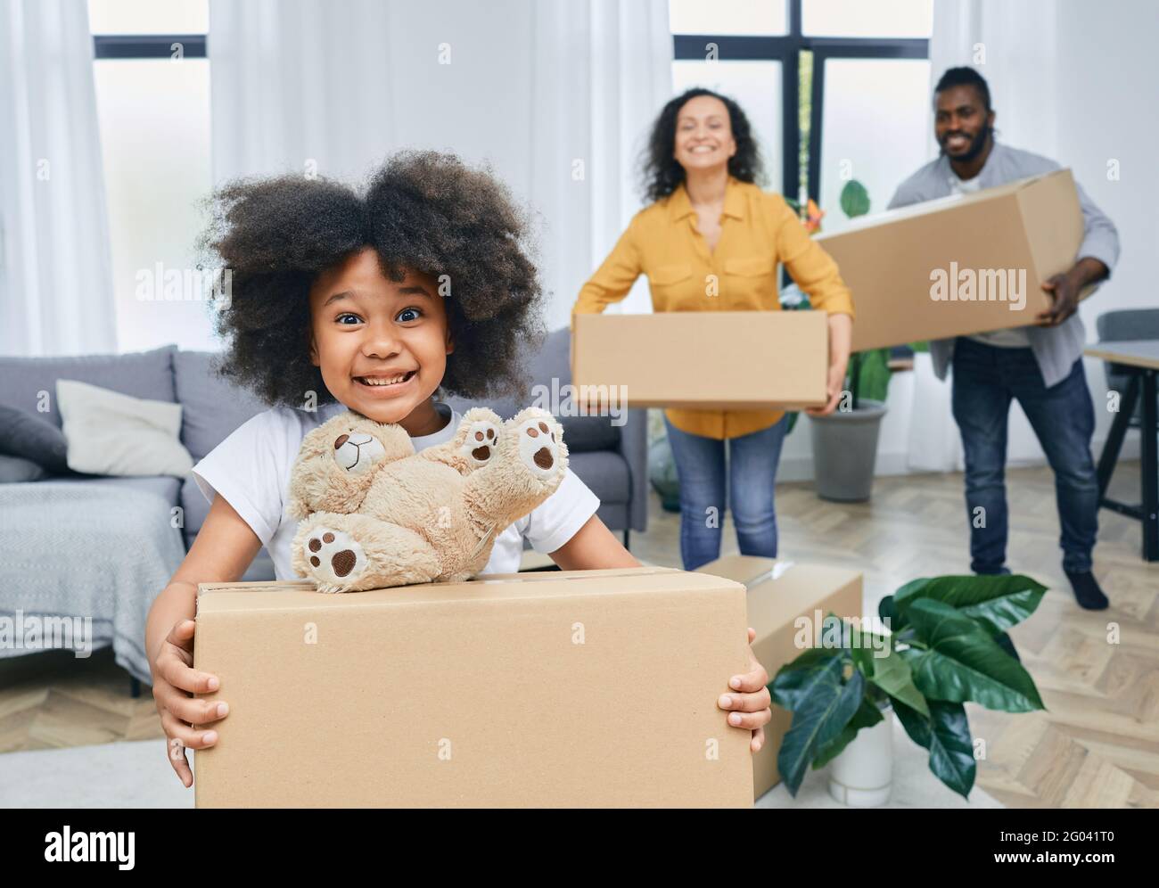Bonne famille afro-américaine avec des boîtes en carton et des choses se déplace vers une nouvelle maison. Acheter ou louer une maison pour une jeune famille Banque D'Images