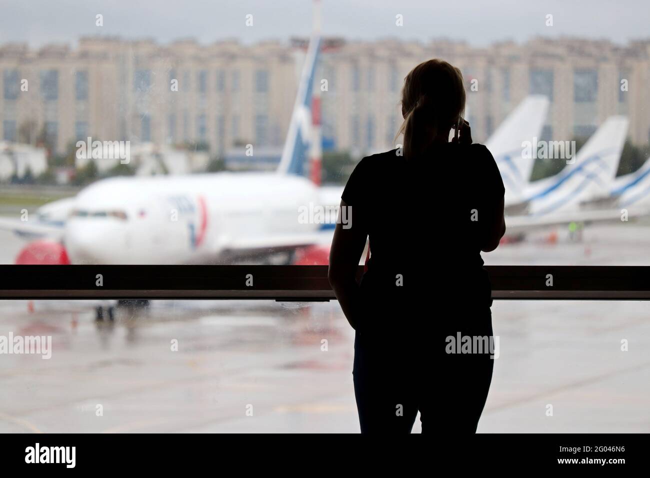Silhouette de femme parlant sur un téléphone portable dans le terminal de l'aéroport. Passager attendant leur vol et regardant les avions par la fenêtre Banque D'Images