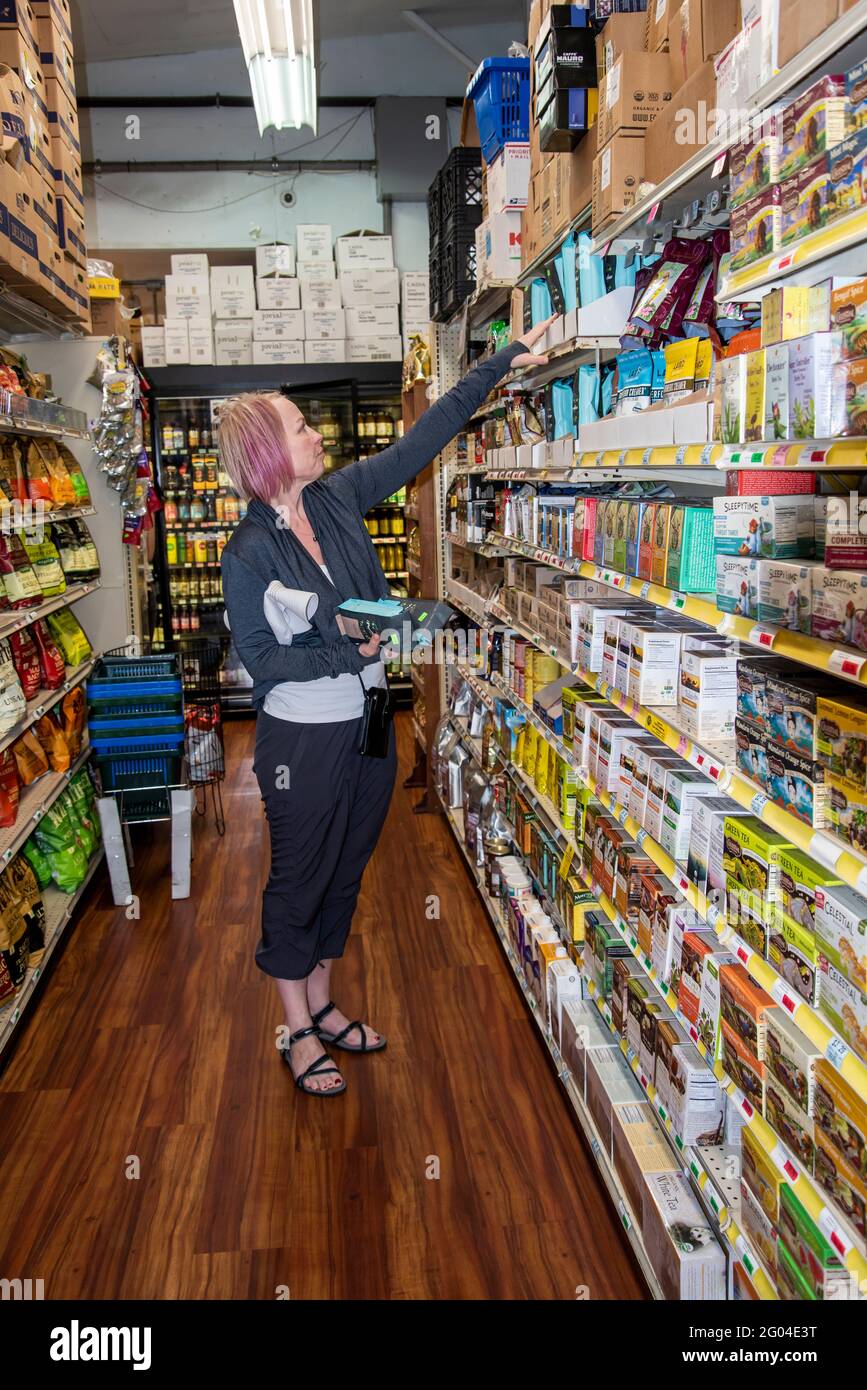 PAIA, Hawaï. Femme d'âge moyen qui vérifie les cafés de spécialité dans une coopérative alimentaire locale. Banque D'Images