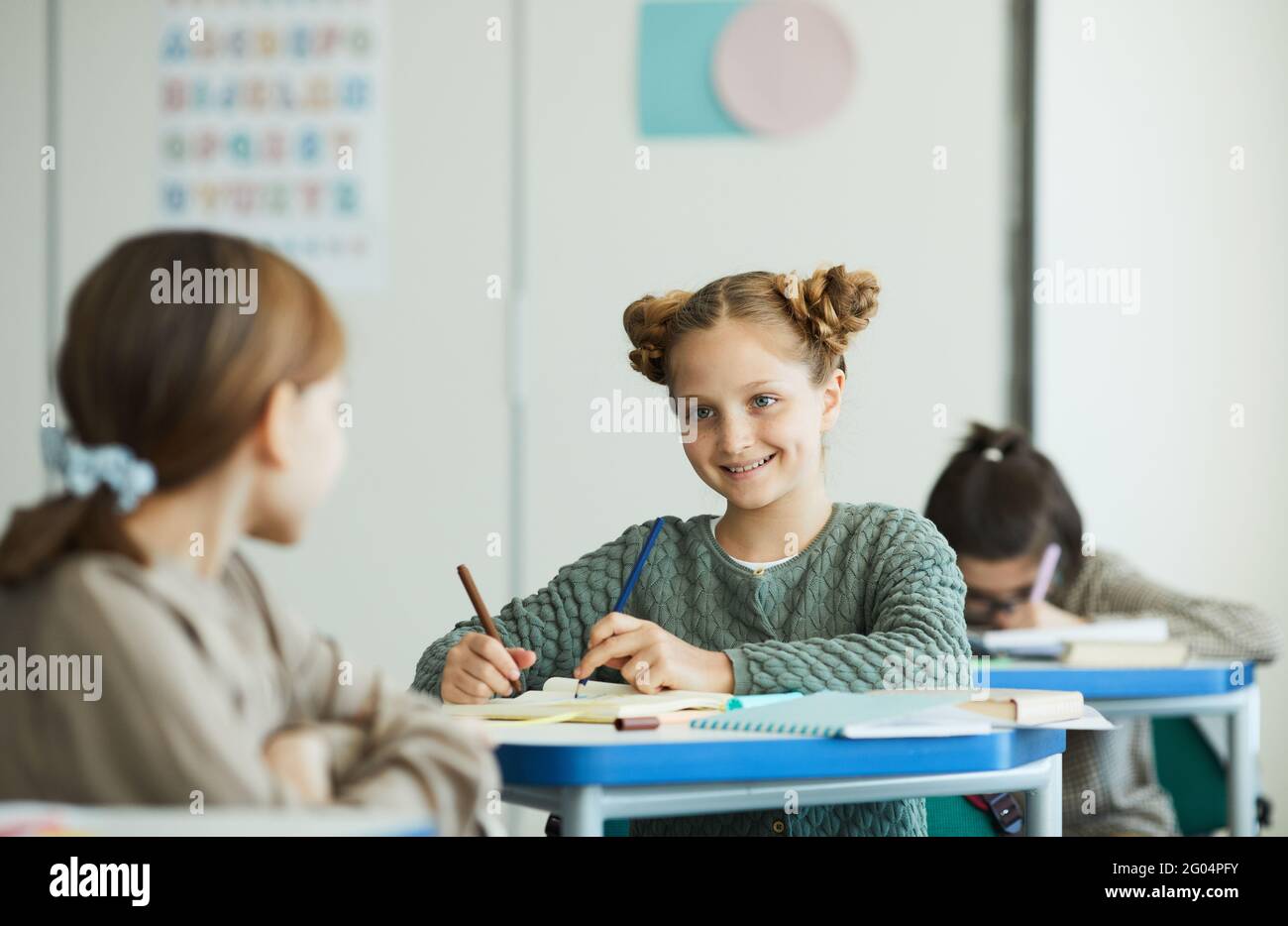 Portrait d'une adolescente souriante parlant à un ami en classe scolaire, espace de copie Banque D'Images