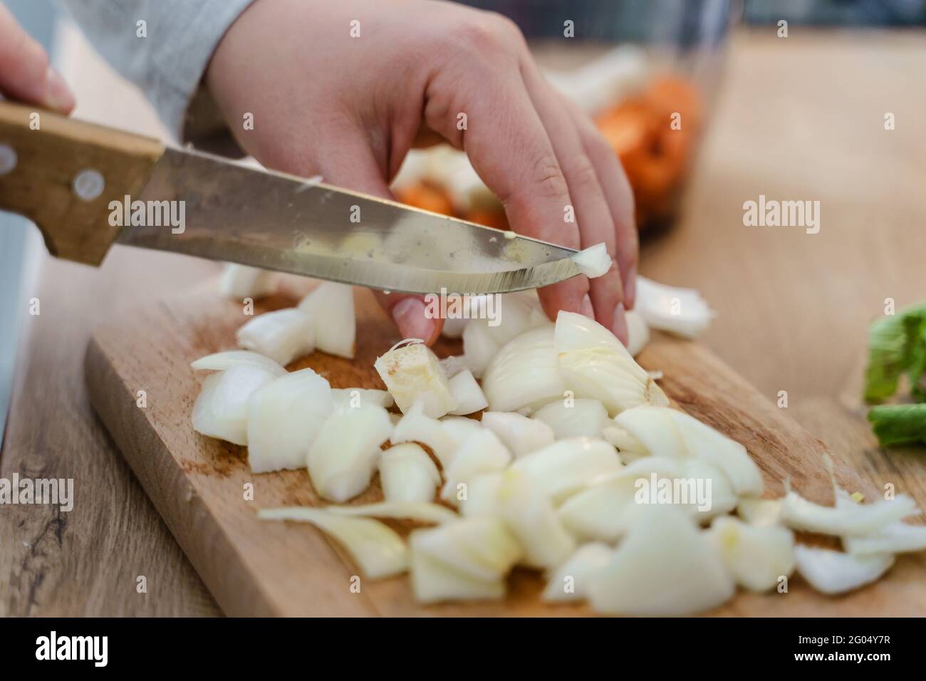 Vue latérale sur les mains d'une femme inconnue avec couteau montez dans la cuisine pour couper des morceaux d'oignon soupe végétalienne ou végétarienne cuisant un repas sain f Banque D'Images