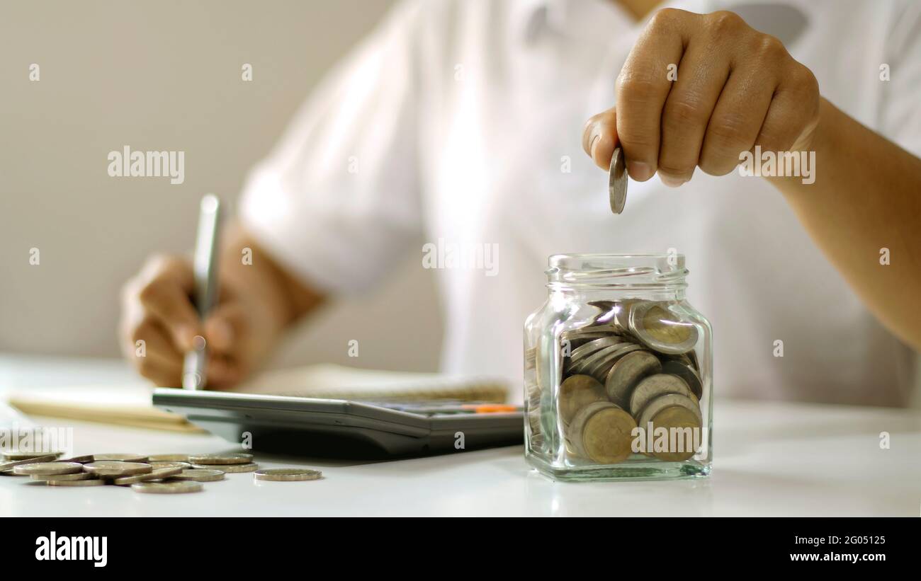 Les gens d'affaires mettent des pièces dans des bouteilles de verre des idées de compte d'épargne et d'argent d'épargne. Banque D'Images