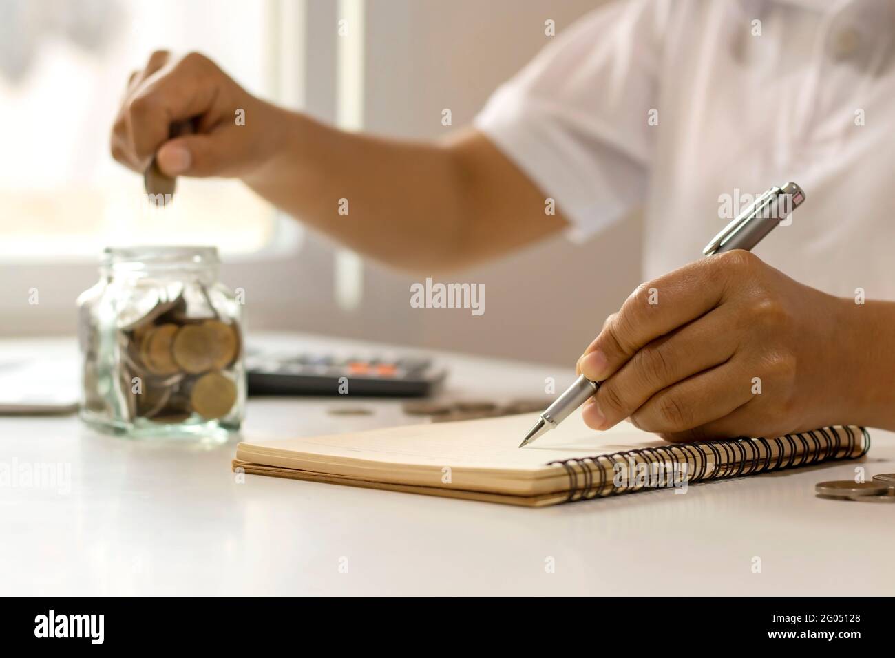 Idée d'économie d'argent. Une main de femme tenant un stylo pour noter les dépenses dans la maison. Banque D'Images