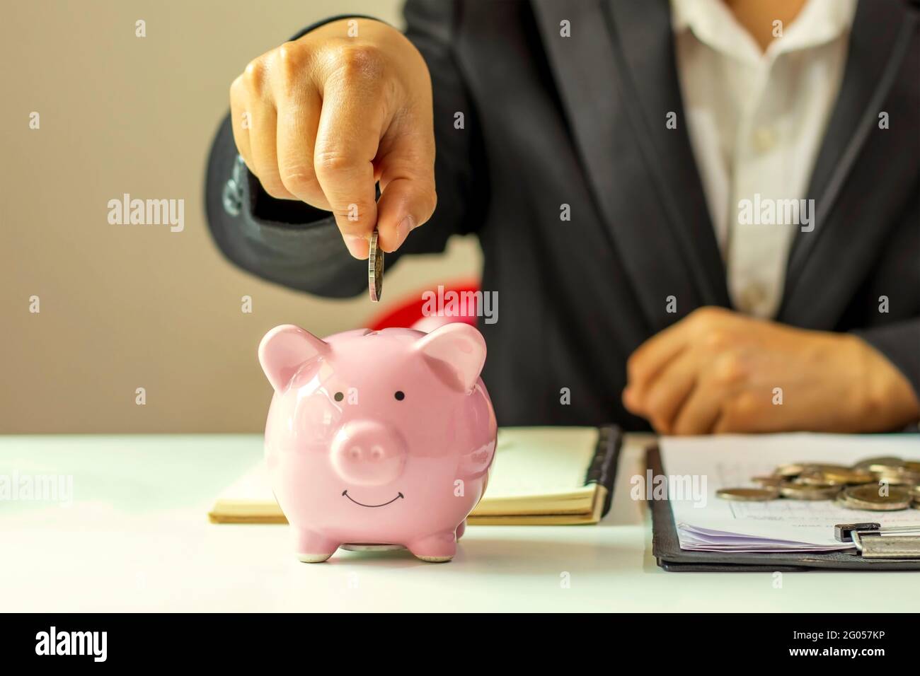 Idées d'épargne et de finance. Les hommes d'affaires mettent des pièces d'argent dans une banque de pigey pour économiser de l'argent et planifier leurs finances. Banque D'Images