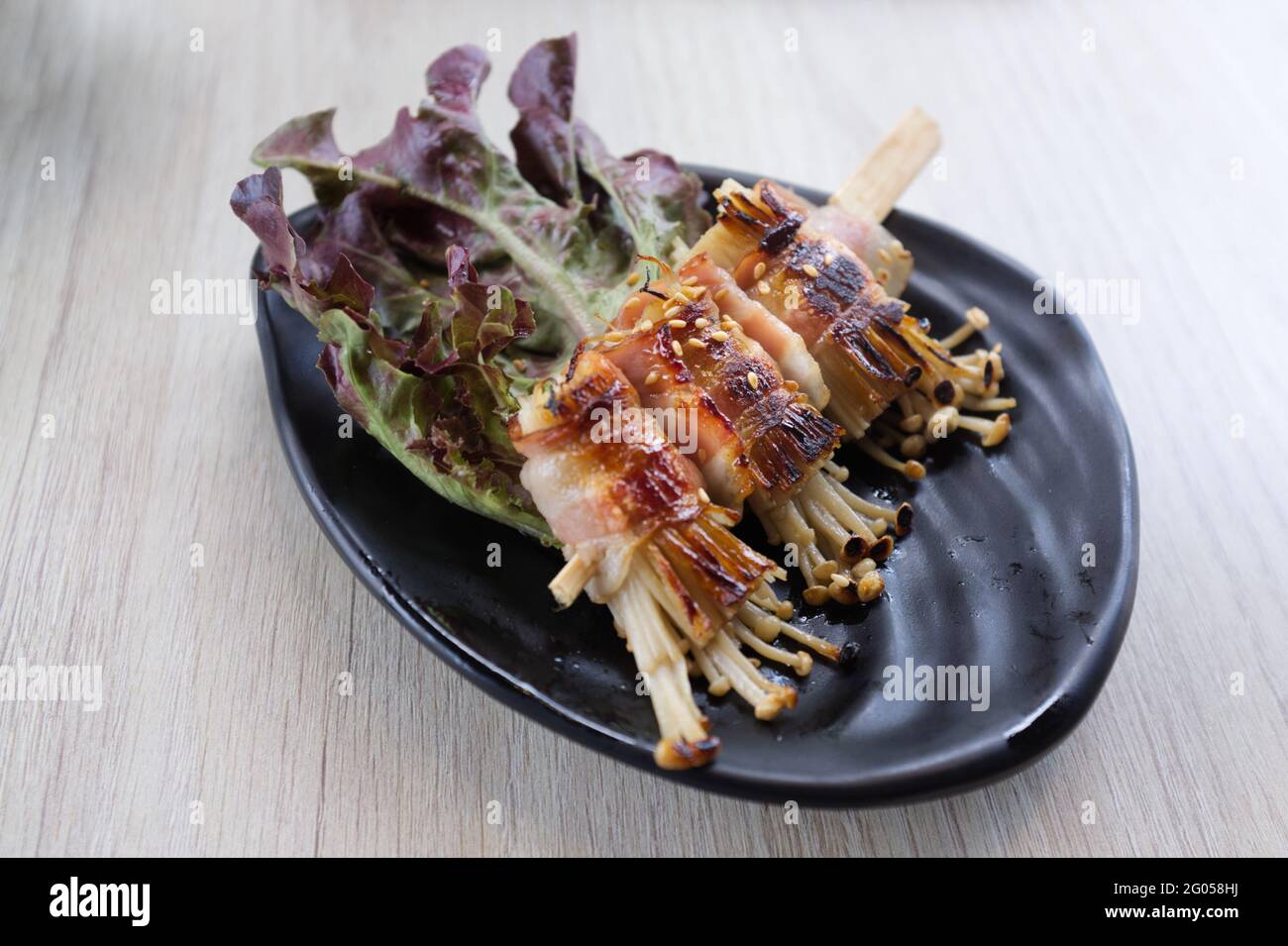 Champignons enoki rôtis au bacon . Cuisine japonaise Banque D'Images