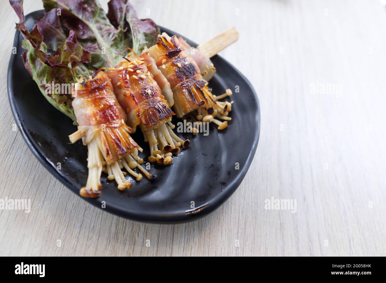 Champignons enoki rôtis au bacon . Cuisine japonaise Banque D'Images