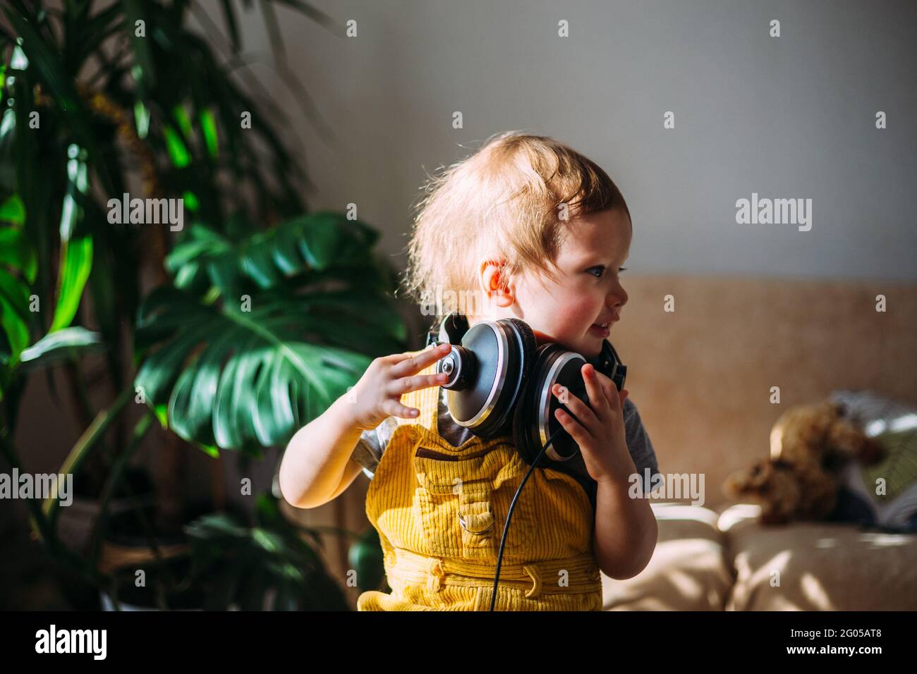 Drôle petit enfant s'amuser avec des écouteurs à la maison, portrait. Banque D'Images