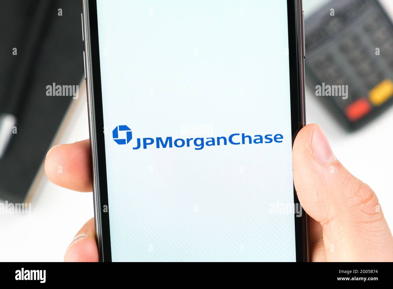 JP Morgan Chase banque logo sur l'écran du smartphone dans la main de mans sur l'arrière-plan du terminal de paiement, mai 2021, San Francisco, Etats-Unis Banque D'Images