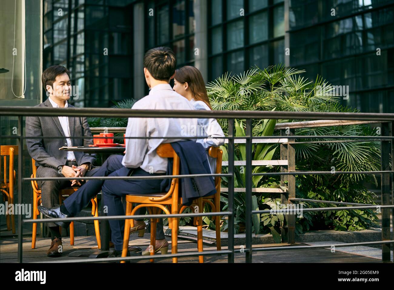 trois hommes d'affaires asiatiques discutent d'affaires dans un café extérieur Banque D'Images