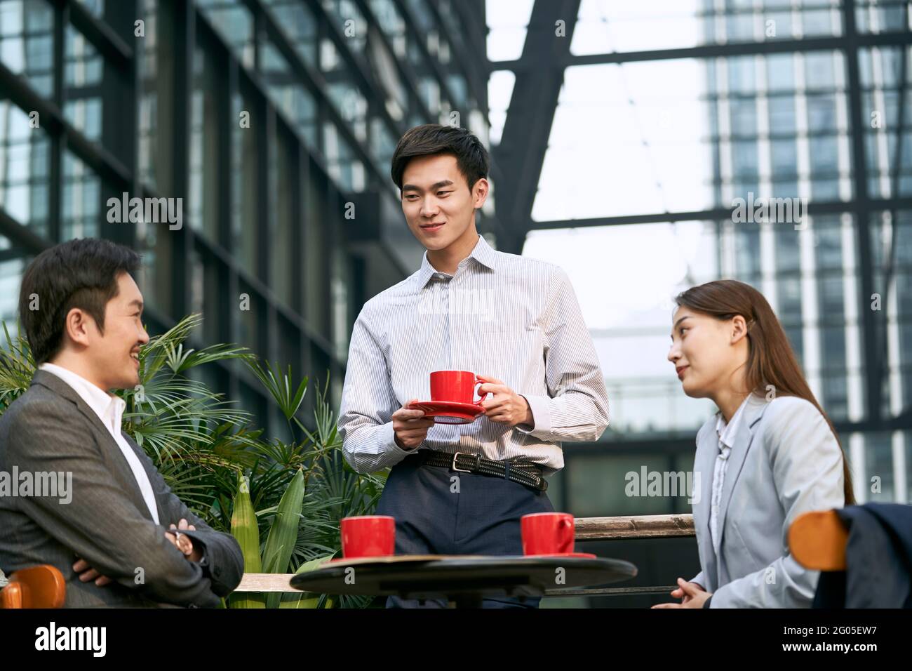 trois hommes d'affaires asiatiques discutant dans un café en plein air heureux et souriant Banque D'Images
