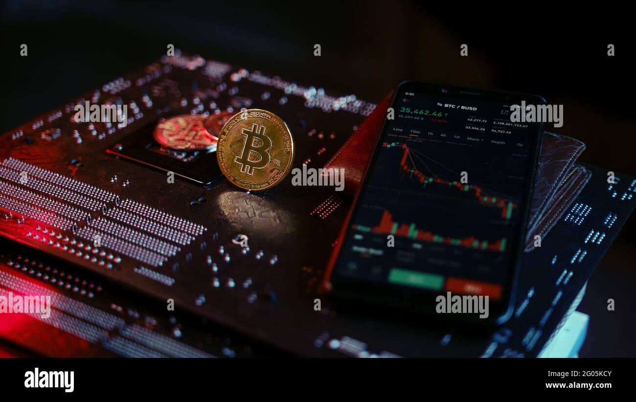 Smartphone avec interface de graphique en bitcoin et crypto sur carte mère lumineuse rouge bleu, concept de finance et de crypto-monnaie Banque D'Images