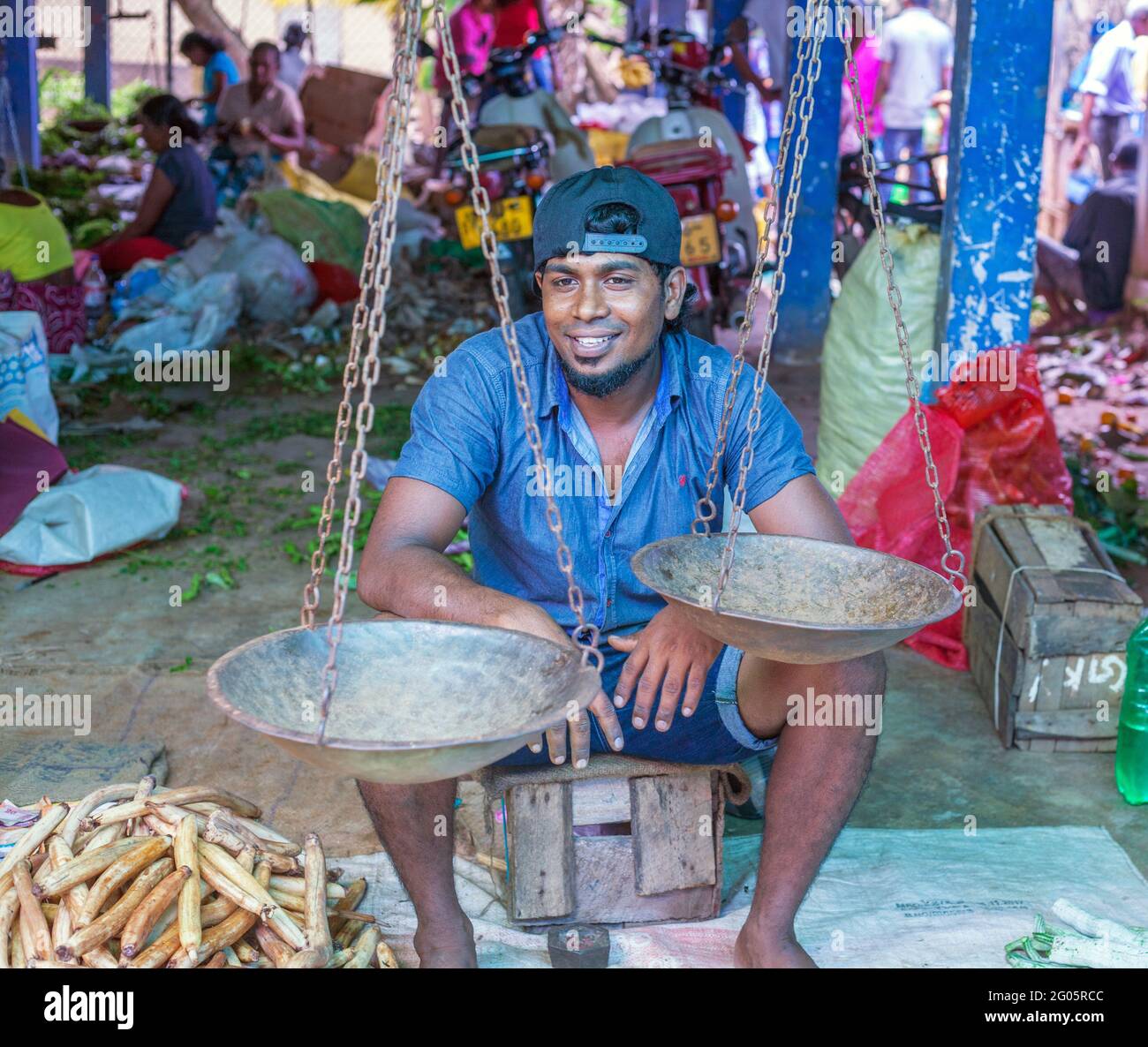 Souriant commerçant sri lankais assis en double denim derrière les balances traditionnelles, Colombo, Sri lanka Banque D'Images