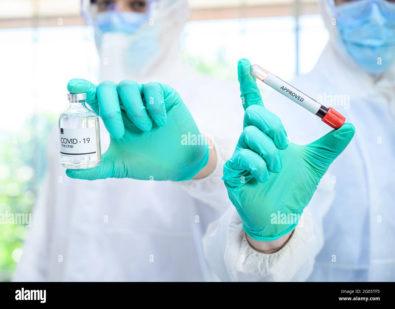 Couple de scientifiques mâles portant une combinaison de protection tenant le vaccin du coronavirus et travaillant avec de nombreux équipements de laboratoire pour la recherche de vaccins en laboratoire. Viru Banque D'Images