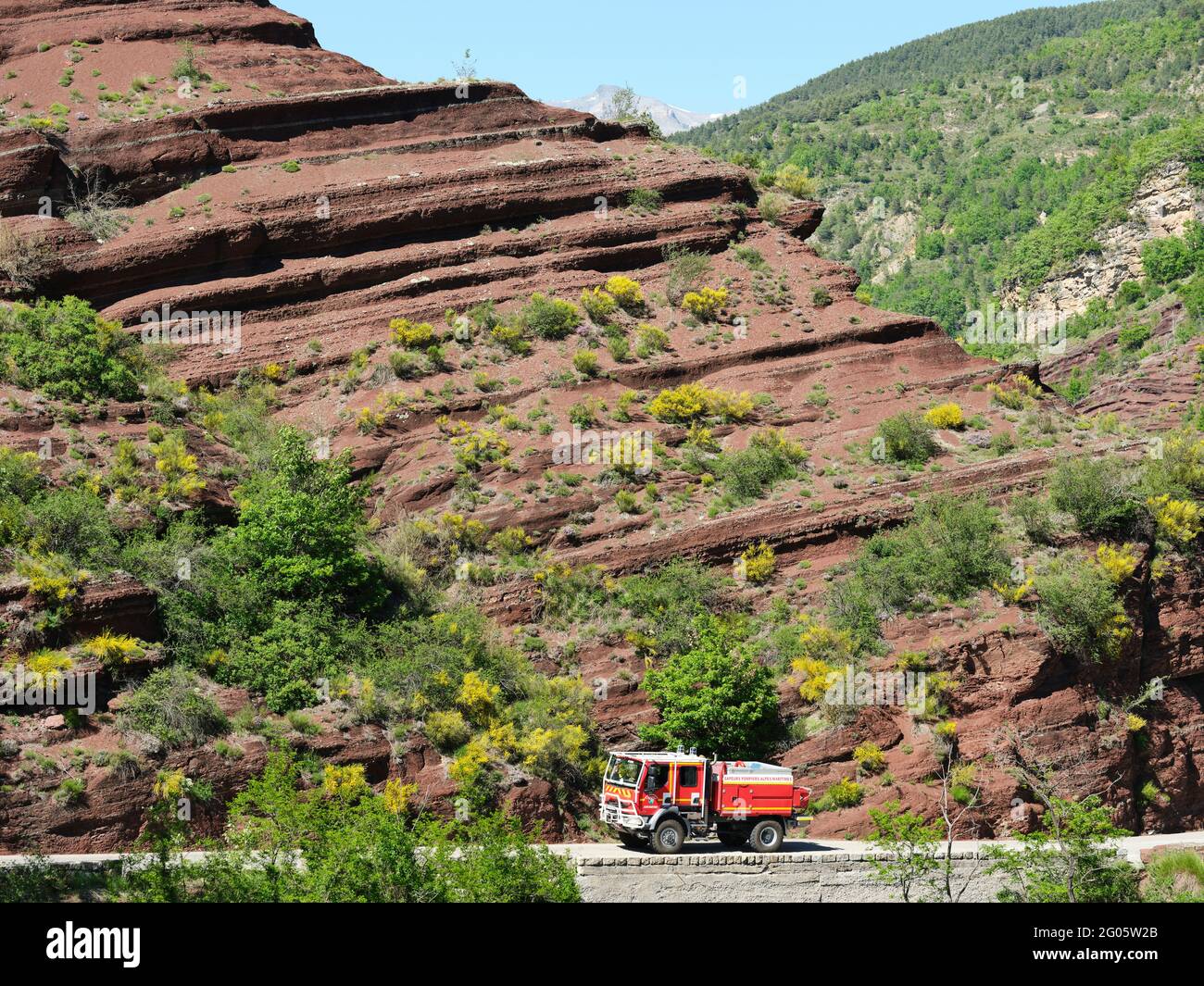 Camion de pompiers tout-terrain avec fond de pompite rouge et balais fleuris. Gorges de Daluis, Guillaumes, Alpes-Maritimes, France. Banque D'Images