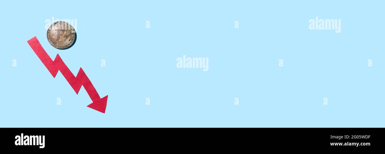 Pièce de monnaie en bitcoin avec une flèche descendante rouge, isolée sur fond bleu avec bannière d'espace de copie. Concept de baisse de prix en devise Crypto. Banque D'Images