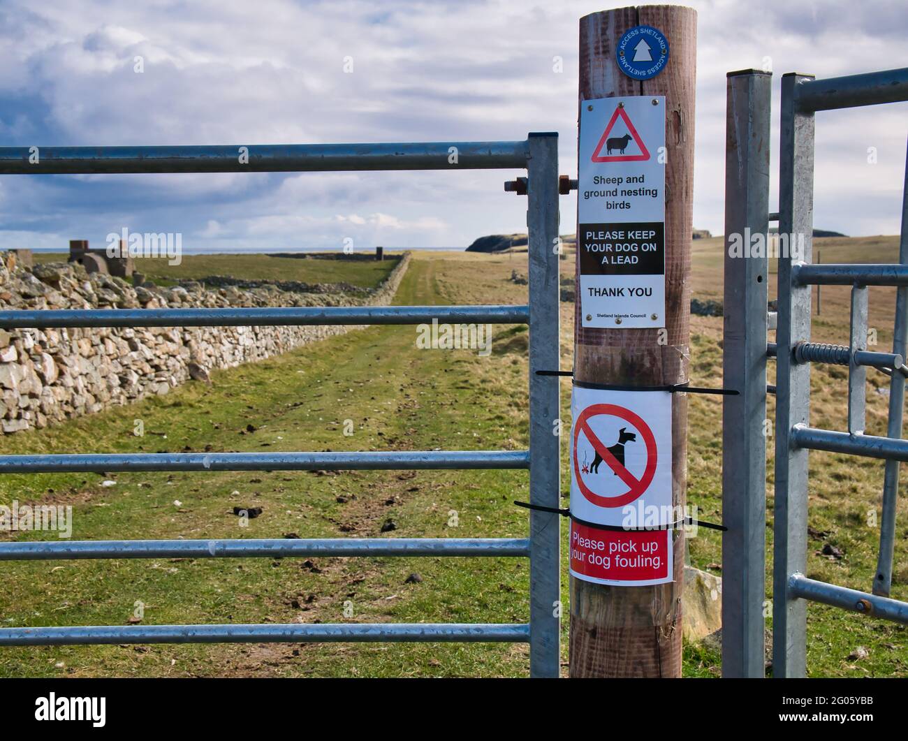 Les panneaux sur un poteau de porte de sentier d'accès Shetland avertissent les propriétaires de chiens d'être au courant des oiseaux nicheurs du sol et de ramasser leur chien qui s'encrasse. Banque D'Images