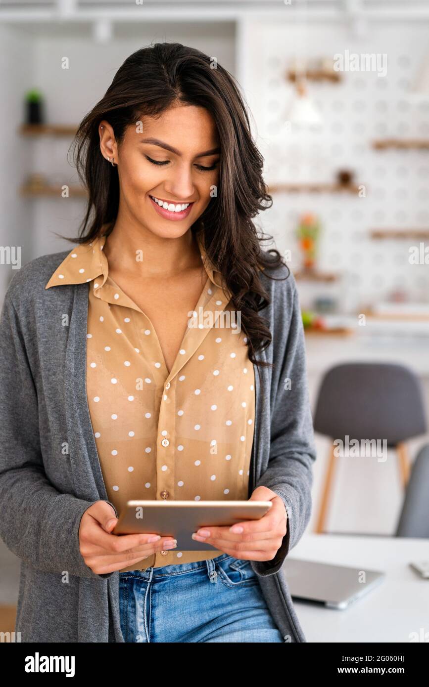 Une belle femme heureuse utilisant un appareil technologique pour travailler, étudier à la maison. L'heure des médias sociaux. Banque D'Images
