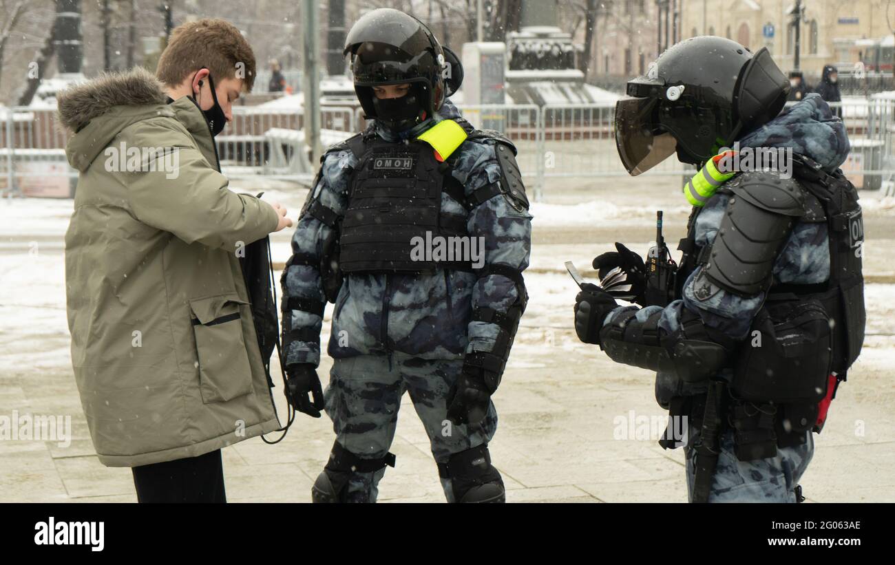 Moscou, Russie - 31 janvier 2021, des policiers en tenue anti-émeute vérifient les documents du jeune homme lors des rassemblements de protestation pour le libre Aleksey Navalny Banque D'Images