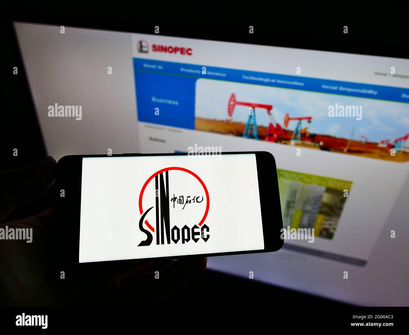Personne tenant un téléphone portable avec le logo de la société China Petrochemical Corporation (Sinopec) sur l'écran devant le site Web. Mise au point sur l'affichage du téléphone. Banque D'Images