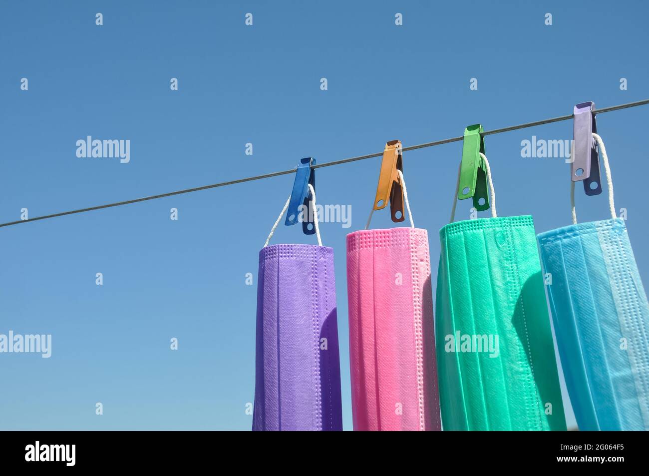 Concept de protéger l'environnement des déchets et de la pollution avec l'espace négatif, photo de masque chirurgical multicolore (masque jetable) accroché à la corde à linge avec la goupille à linge. Banque D'Images