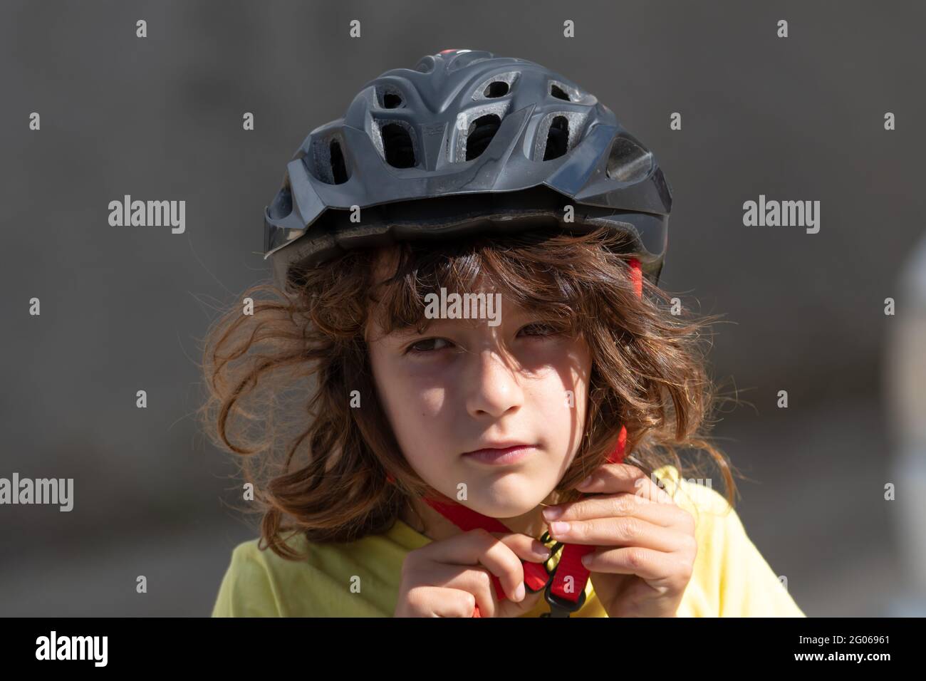 portrait d'un petit garçon aux cheveux longs fixe son casque de sécurité  rouge prêt à monter à vélo Photo Stock - Alamy