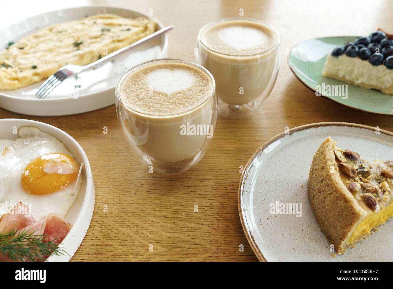 Petit déjeuner lumineux sur fond de bois marron, vue sur le dessus. Desserts savoureux, omelette, œufs frits, café. Banque D'Images