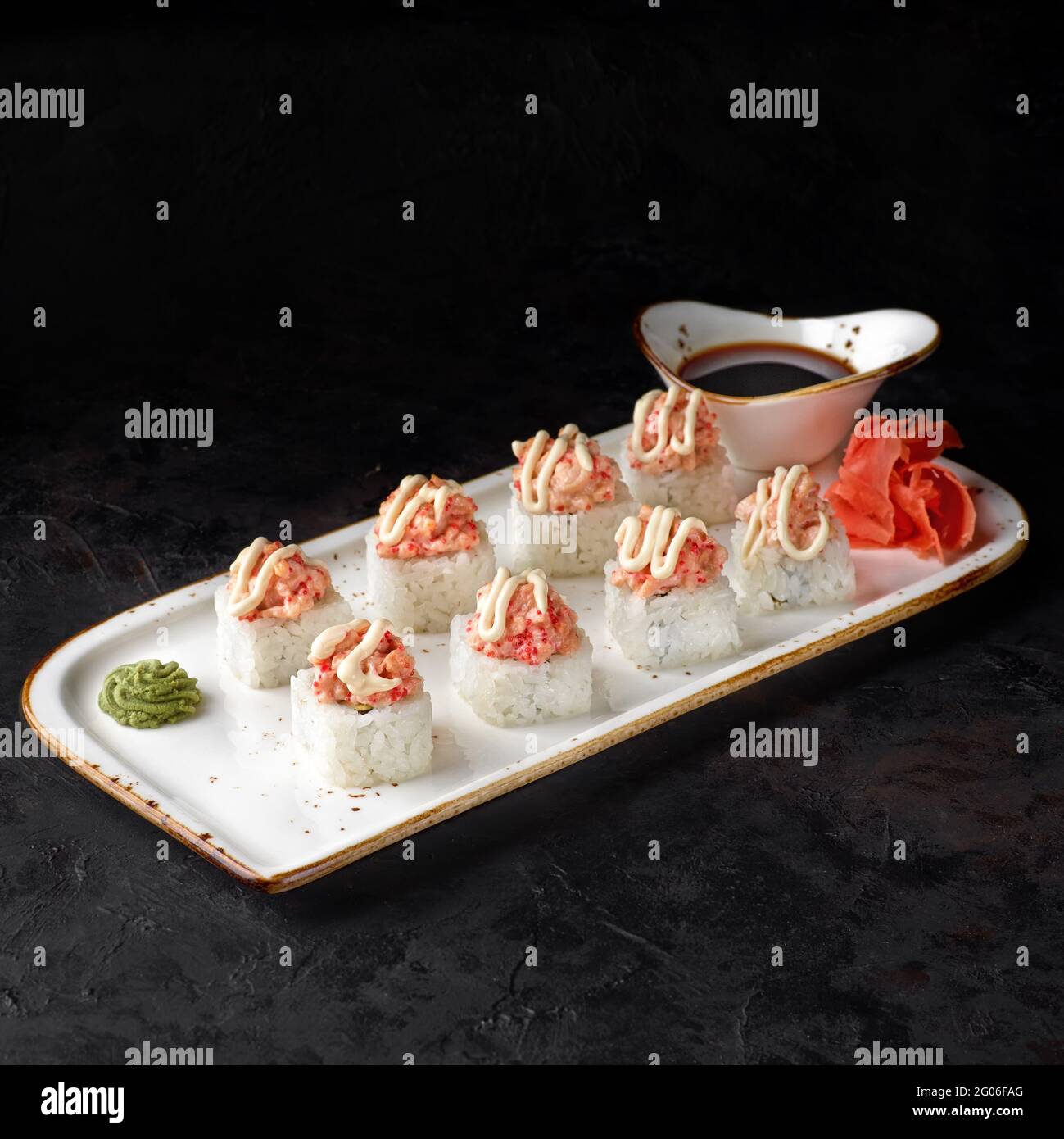 Roulé au saumon. Rouler avec du fromage caillé, du concombre, de l'avocat et du saumon au four avec du caviar tobiko sur fond noir. Menu sushi. Japonais foo Banque D'Images
