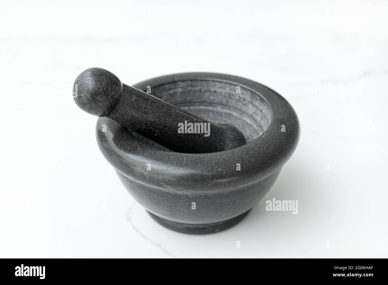 Mortier et pilon en pierre noire isolés sur une table en marbre blanc Banque D'Images