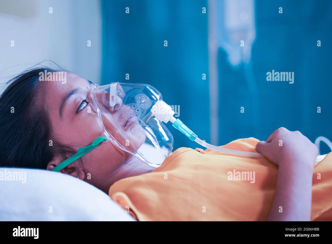 Vue latérale de la petite fille qui respire sur le masque d'oxygène du ventilateur en raison du coronavirus Covid-19 essoufflement ou dyspnée - concept d'enfants soins de santé Banque D'Images