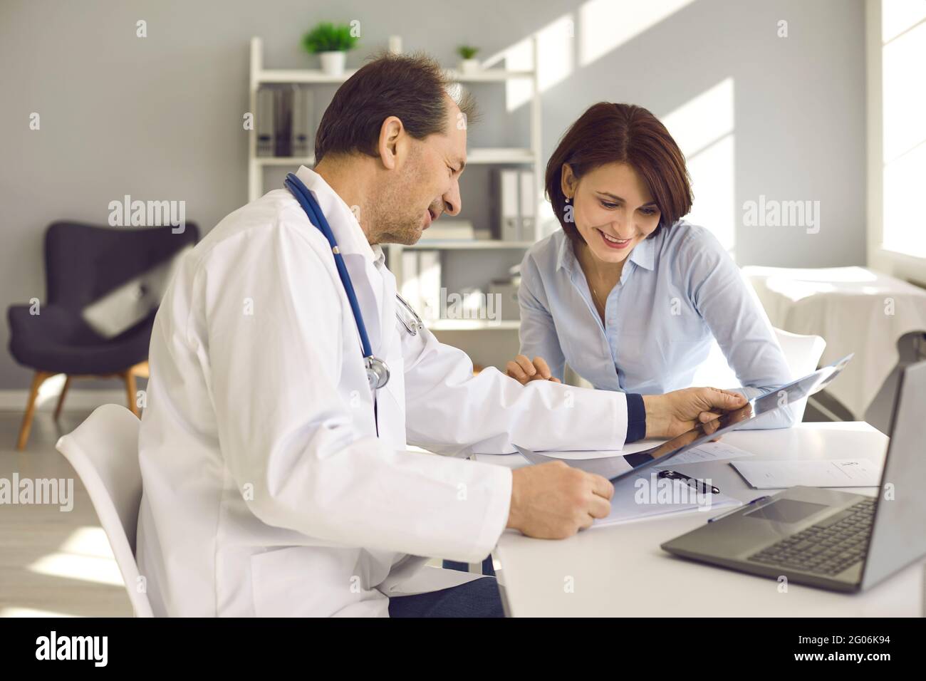 Bonne femme à l'écoute d'un médecin et à la recherche d'IRM ou de rayons X avec de bons résultats Banque D'Images