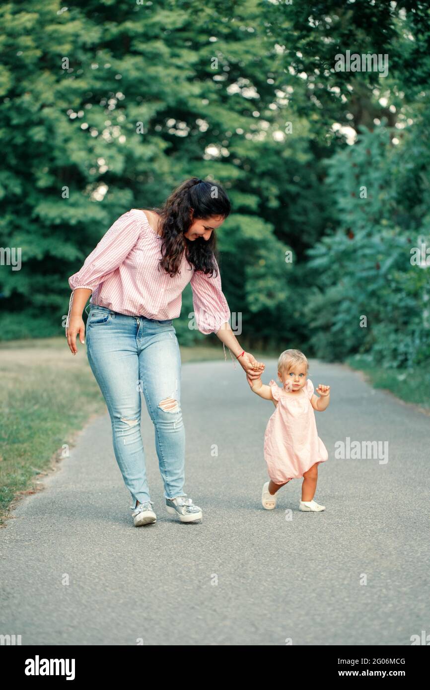 Premiers Pas De Bebe Petite Fille Adorable Apprendre A Marcher Et A Tenir Sa Main De Mere Maman Aidant Enfant Enfant Fille A Aller Dans Le Parc A L Exterieur L Ete Photo Stock