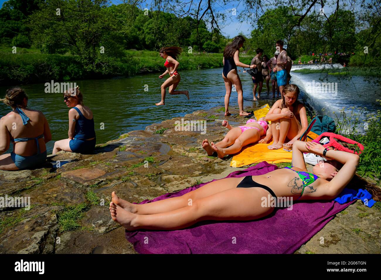 Une femme saute dans l'eau tandis que les gens baignent de soleil par temps chaud à Warleigh Weir, Bath, le premier jour de l'été météorologique. Date de la photo: Mardi 1er juin 2021. Banque D'Images