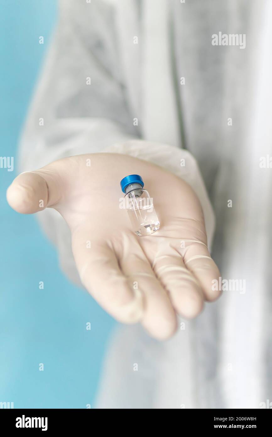 La main d'un médecin ou d'une infirmière dans un gant contient un vaccin contre le coronavirus. Concept de vaccination, de médecine, de soins de santé. Le médecin offre le médicament dans un A. Banque D'Images