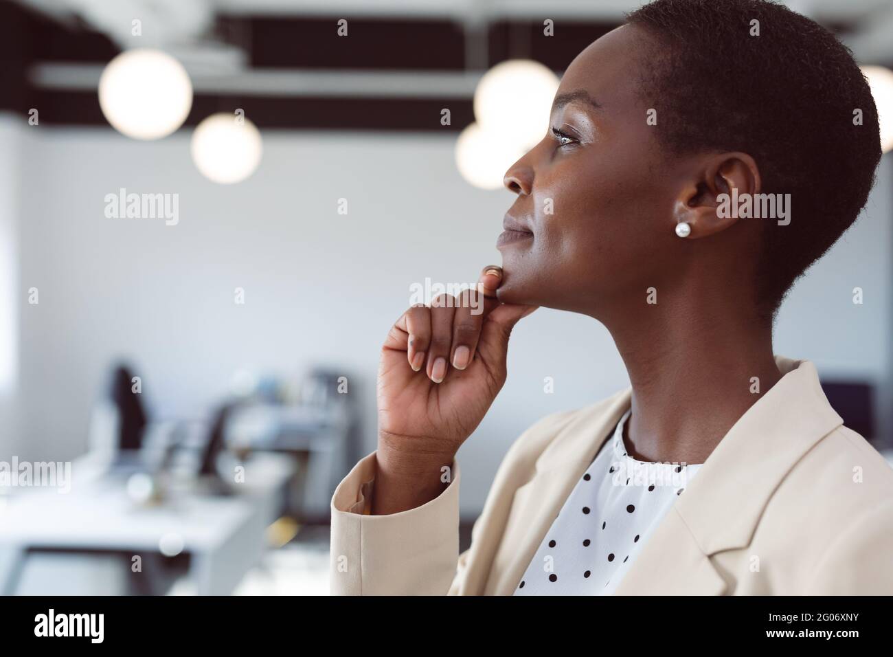 Femme d'affaires afro-américaine qui pense, touchant le menton au travail Banque D'Images