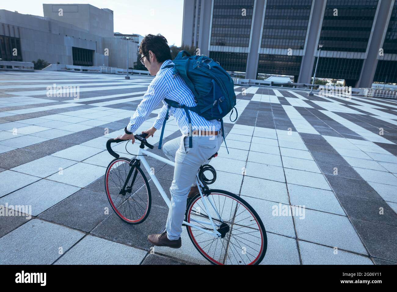 Homme d'affaires asiatique à vélo dans la rue de la ville avec des bâtiments modernes en arrière-plan Banque D'Images