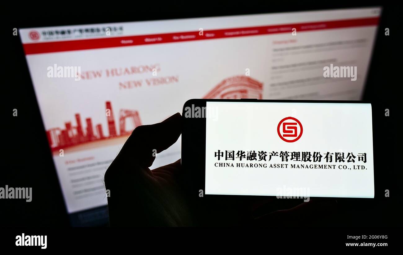 Personne tenant un smartphone avec le logo de China Huarong Asset Management Co. Ltd. Sur l'écran devant le site Web. Mise au point sur l'affichage du téléphone. Banque D'Images