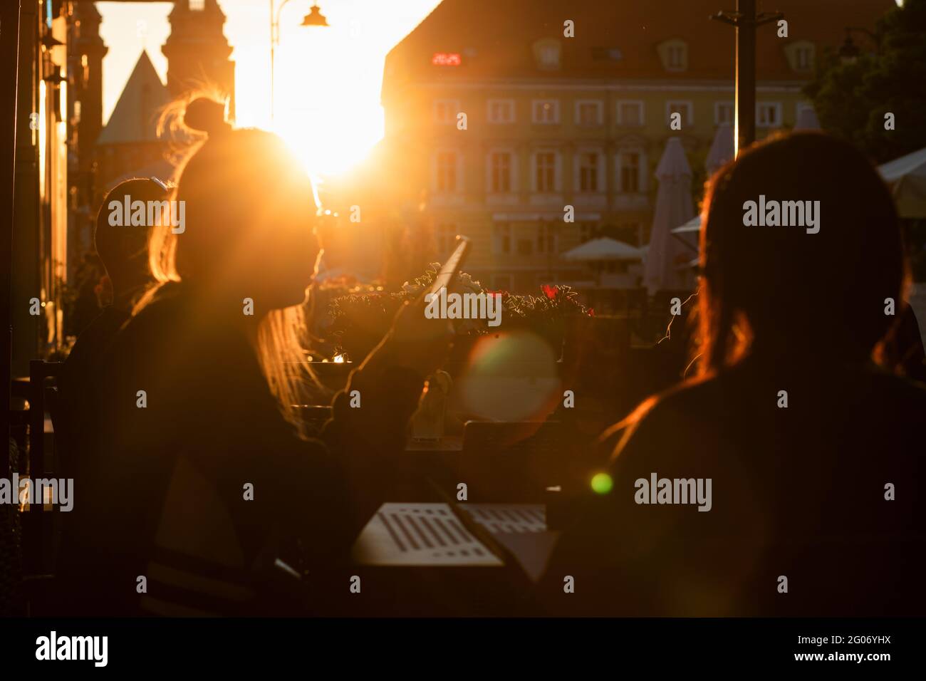 Gniezno, Pologne - Silhouettes de filles assises à une table dans un pub, sur fond de soleil couchant. Banque D'Images