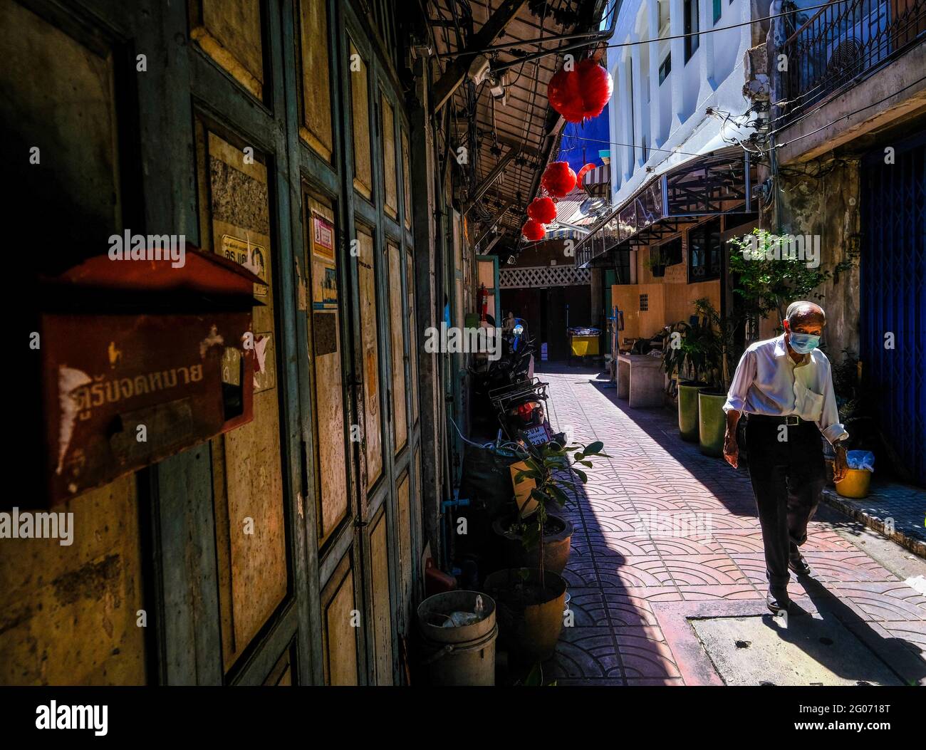 Un homme âgé marche le long d'une allée ensoleillée dans le quartier chinois de Bangkok, en Thaïlande Banque D'Images