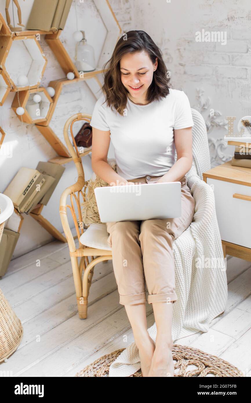 une jeune femme attrayante dans un appartement lumineux et moderne utilise un ordinateur portable pour communiquer ou étudier en ligne Banque D'Images