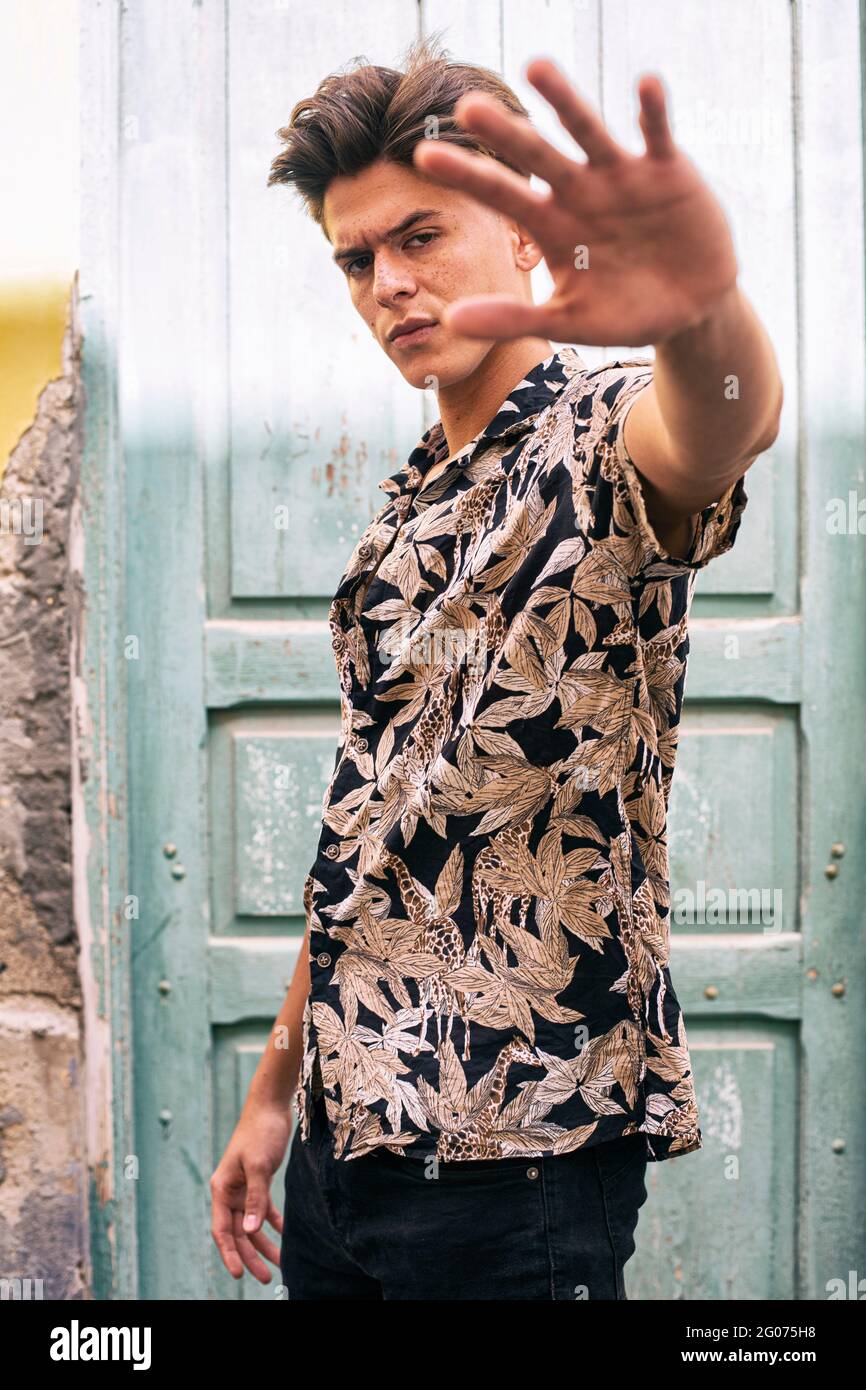 Portrait d'un jeune homme marchant dans la rue en essayant de cacher son visage avec sa main. Banque D'Images