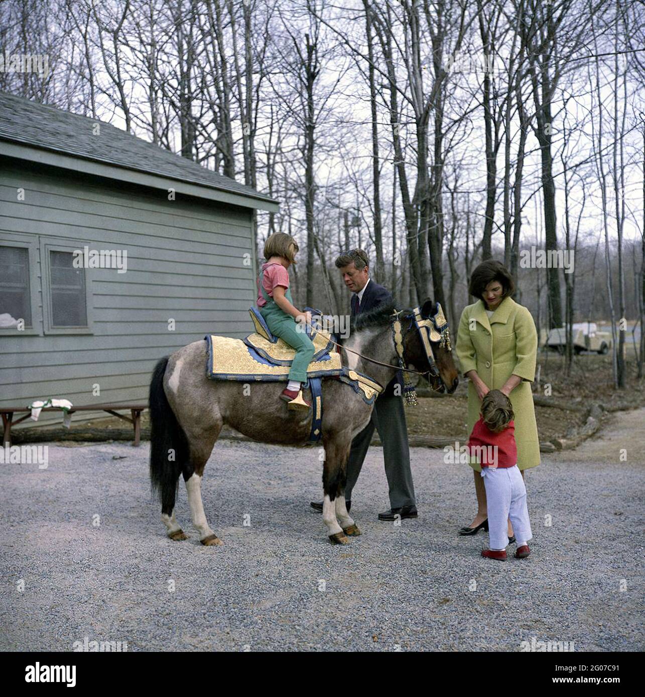 31 mars 1963 week-end au Camp David. Le Président Kennedy et Mme Kennedy avec leurs enfants, Caroline et John, Jr., à Camp David, Maryland. Caroline est assise sur 'Macaroni'. La selle sur Macaroni était un don du roi Hassan II de Morroco. Banque D'Images