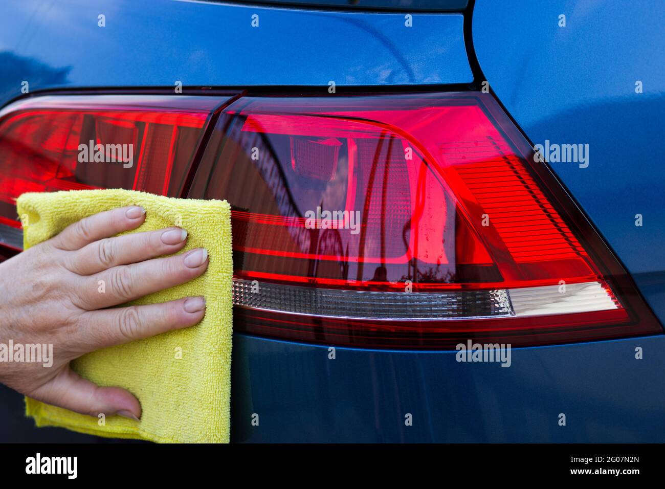 Main des employés le travailleur utilise un chiffon jaune propre pour essuyer la voiture après avoir lavé dans le magasin de lavage de voiture. Banque D'Images