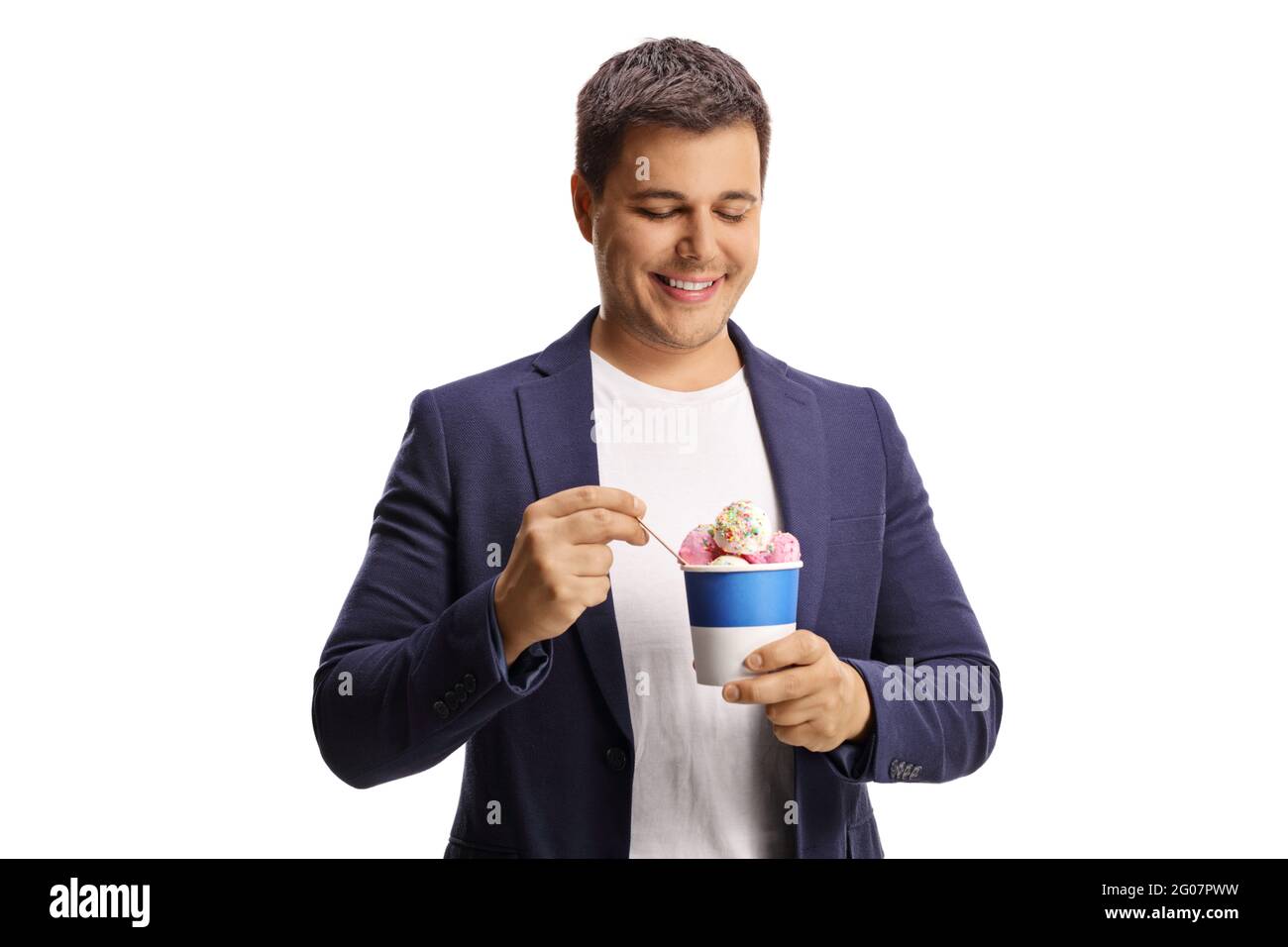 Jeune homme souriant qui mange de la glace dans une tasse en papier isolée sur fond blanc Banque D'Images