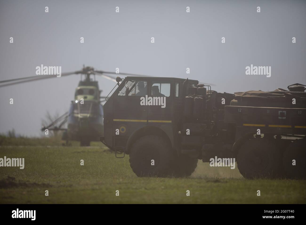 Smardan, Roumanie - 11 mai 2021 : camion et hélicoptère de l'armée roumaine dans un nuage de poussière au stand de tir militaire de Smardan. Banque D'Images