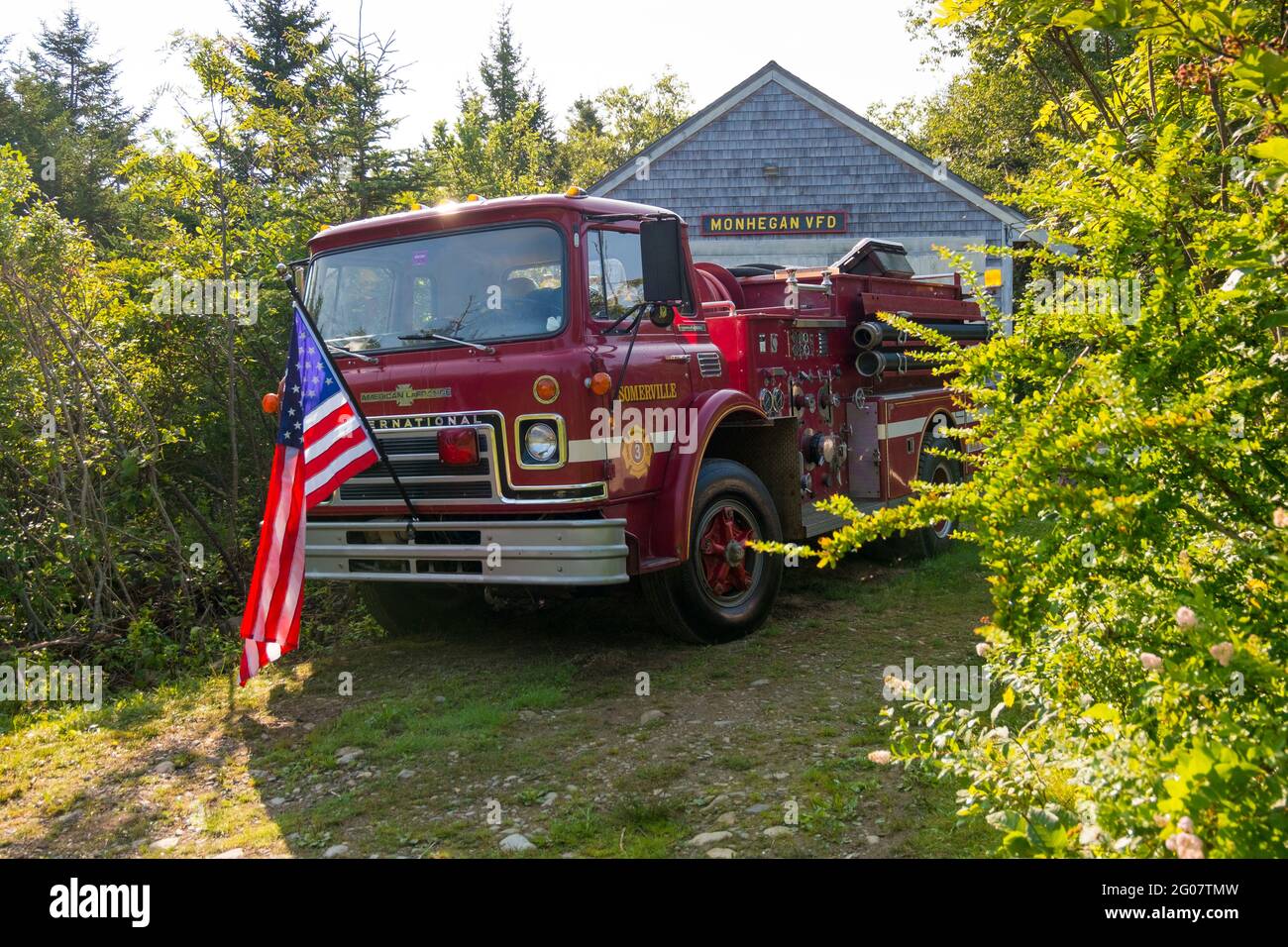 Un camion d'incendie rouge Somerville avec un drapeau américain est stationné devant le VFD, service d'incendie volontaire. Sur l'île Monhegan dans le Maine. Banque D'Images
