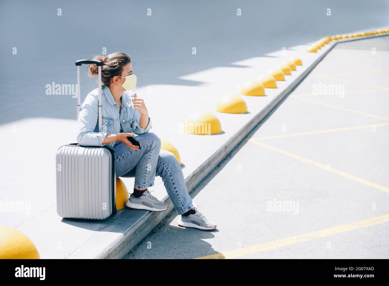Femme endormi voyageur dans des vêtements décontractés à la gare en attendant un bus ou un taxi. Concept vacances d'été et Road trip pour jeunes voyageurs célibataires Banque D'Images
