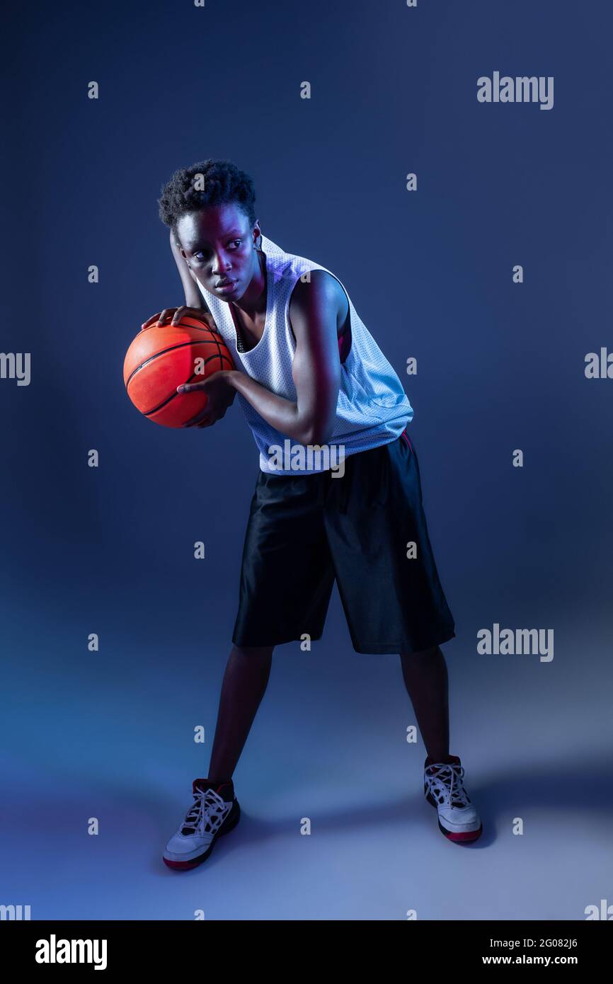 Femme noire avec tenue de basket ball dans le studio utilisant des