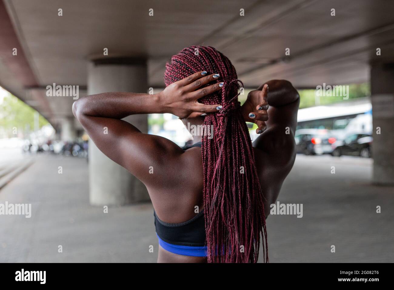 Vue arrière de l'ethnie Sportswoman fixant les cheveux et se préparant à l'entraînement sur le parking Banque D'Images